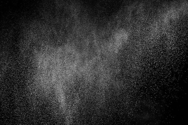Замораживание движения белых частиц на черном фоне. Взрыв порошка. Абстрактная пылевая текстура.