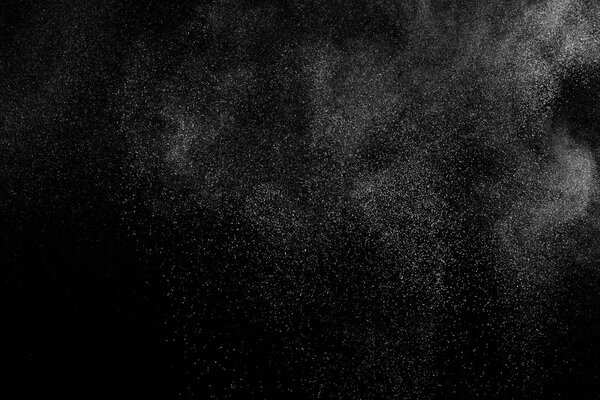 Замораживание движения белых частиц на черном фоне. Взрыв порошка. Абстрактная пылевая текстура.