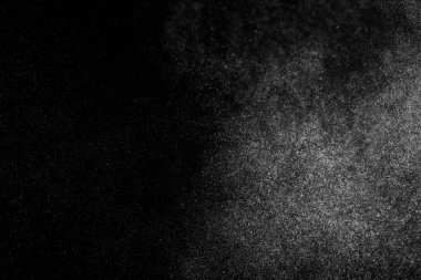 Siyah zemin üzerindeki beyaz parçacıkların hareketlerini dondur. Barut patlaması. Soyut toz tabakası dokusu.