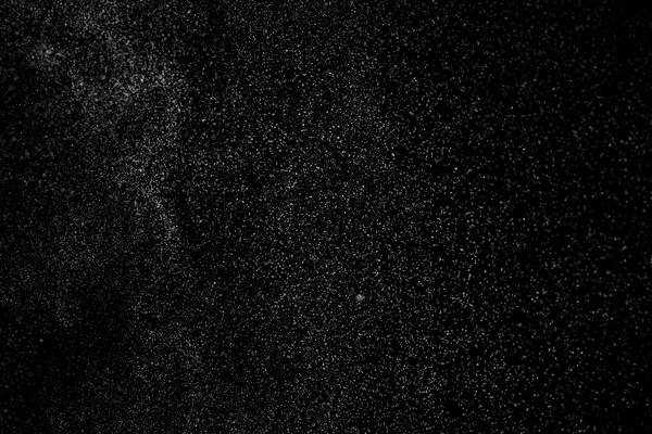 Siyah arka planda soyut su sıçramaları. Beyaz parçacıkların hareketlerini dondur. Yağmur, kar örtüsü dokusu.