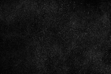 Siyah arka planda soyut su sıçramaları. Beyaz parçacıkların hareketlerini dondur. Yağmur, kar örtüsü dokusu.