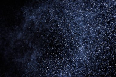 Siyah arka plan üzerine su sıçramalarına soyut mavi. Beyaz parçacıkların hareket dondurmak. Yağmur, kar doku yerleşimi..