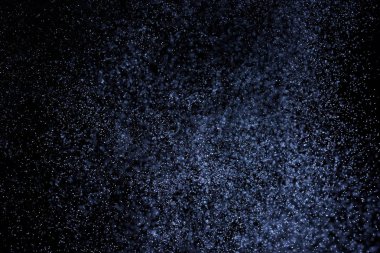 Siyah arka plan üzerine su sıçramalarına soyut mavi. Beyaz parçacıkların hareket dondurmak. Yağmur, kar doku yerleşimi..