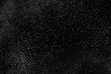 Siyah arka planda soyut su sıçramaları. Beyaz parçacıkların hareketlerini dondur. Yağmur, kar örtüsü dokusu.