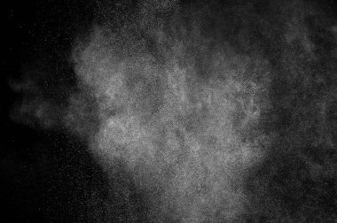 Siyah zemin üzerindeki beyaz parçacıkların hareketlerini dondur. Barut patlaması. Soyut toz tabakası dokusu.