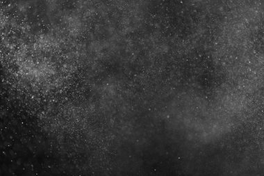 Siyah arka planda soyut su sıçramaları. Beyaz parçacıkların hareketlerini dondur. Yağmur, kar örtüsü dokusu.