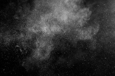 Siyah zemin üzerindeki beyaz parçacıkların hareketlerini dondur. Barut patlaması. Soyut toz tabakası dokusu. 