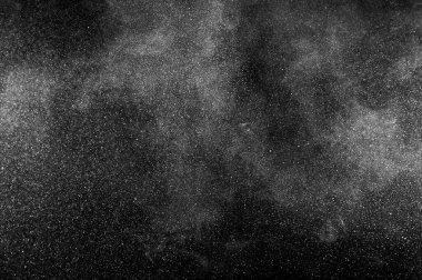 Siyah zemin üzerindeki beyaz parçacıkların hareketlerini dondur. Barut patlaması. Soyut toz tabakası dokusu. 