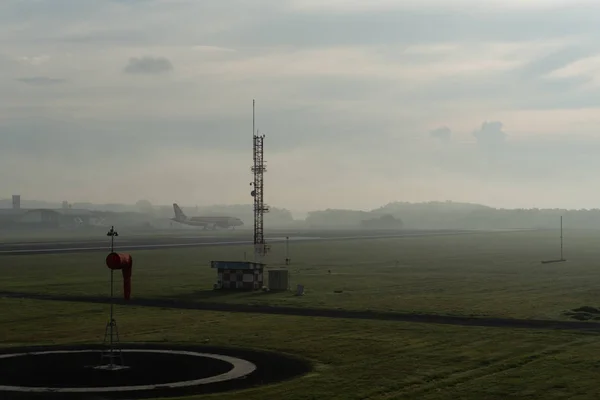 BADUNG / BALI-ABRIL 14 2019: Un paisaje de jardín meteorológico en el aeropuerto de Ngurah Rai Bali por la mañana cuando el cielo lleno de nubes de cirros grises y un avión está aterrizando —  Fotos de Stock