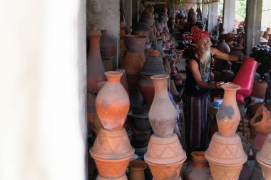 UBUD, BALI-APRIL 27 2019, beyaz sakallı, kafasında etnik kravat olan bir çömlekçi çömlek galerisinde çömlekçiliğini boyuyor.