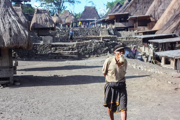 FLORES / INDONESIA-NOVEMBER 06 2012: Een landschap van een oud dorp genaamd Bena dorp in Flores en een grootvader gekleed in een vintage witte baard en roken zijn sigaret. Dit dorp gebruikt nog steeds meg. — Stockfoto