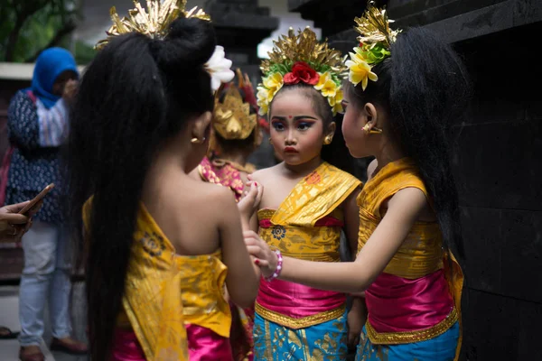 BALI / INDONESIA-DECEMBER 28 2017: Троє молодих балійських танцюристів, одягнених у традиційний балійський одяг і макіяж, готуються виступити на сцені. Один з них виглядає знервованим. Це вільна подія. — стокове фото