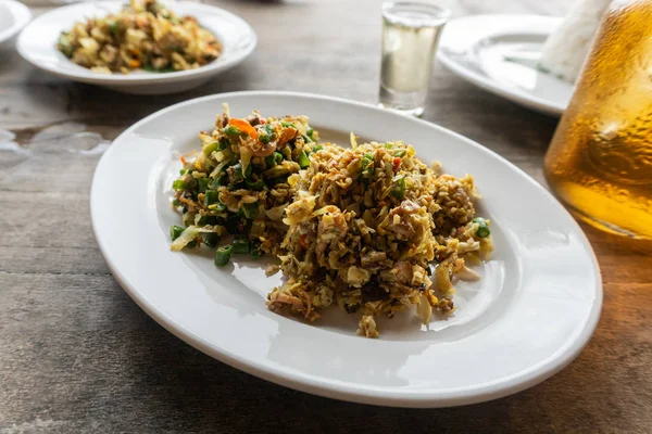 Traditionelles balinesisches Essen namens lawar. lawar ist Hackfleisch, das mit Gemüse, langen Bohnen und Gewürzen gemischt und dann gleichmäßig gerührt wird. auf einem Teller am Holztisch serviert — Stockfoto