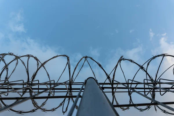 BALI / INDONESIA-JUNIO 01 2019: Valla de alambre de púas con cielo azul brillante para sentirse en silencio y solo y quieren libertad. Nubes dramáticas detrás de una cerca de alambre de púas en un muro de la prisión. Valla alrededor de área restringida —  Fotos de Stock