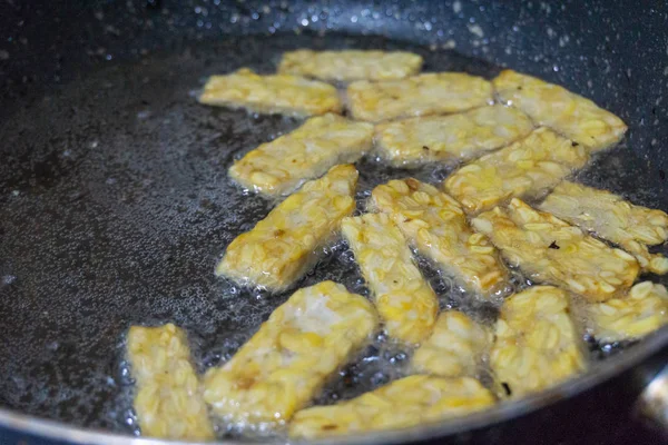 A comida culinária tradicional indonésia fritou tempeh, uma comida culinária indonésia tradicional. Isso é simples e muitas vezes feito em casa. Está fritando na panela com um monte de óleo de cozinha — Fotografia de Stock