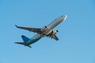 BALI / INDONESIA-JUNE 06 2019: Endonezya 'da gökyüzü ekibine katılan havayollarından biri olan Garuda Endonezya mavi gökyüzünde uçuyor. İniş takımları depolanma aşamasında