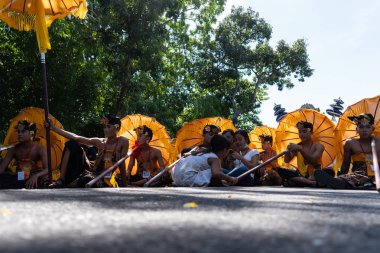 Denpasar/Endonezya-15 Haziran 2019: Tapınak festivali sırasında Hindu tören geçit töreninde geleneksel renkli şemsiyeler ile etnik kostümlü Balili dansçı grubu. Bali halkı kültürü