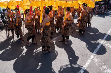 Denpasar/Endonezya-15 Haziran 2019: Tapınak festivali sırasında Hindu tören geçit töreninde geleneksel renkli şemsiyeler ile etnik kostümlü Balili dansçı grubu. Bali halkı kültürü