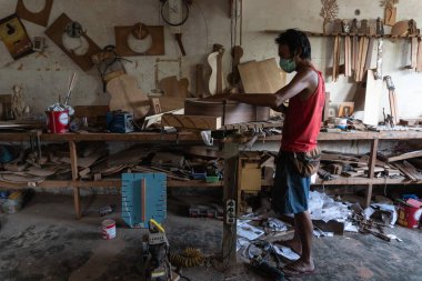 Gianyar,Bali/Endonezya-30 Mayıs 2019: Bir gitar ustası Guwang Village, Gianyar, Bali'de I Wayan Tuges'e ait ahşap gitar atölyesinde ahşaptan klasik gitarlar yapıyor.