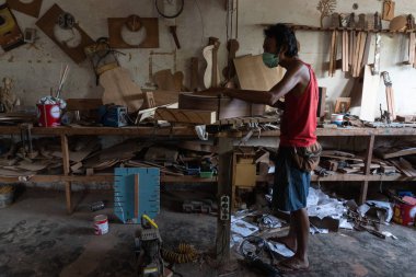Gianyar,Bali/Endonezya-30 Mayıs 2019: Bir gitar ustası Guwang Village, Gianyar, Bali'de I Wayan Tuges'e ait ahşap gitar atölyesinde ahşaptan klasik gitarlar yapıyor.