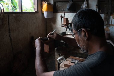 Gianyar,Bali/Endonezya-30 Mayıs 2019: Guwang Village, Gianyar, Bali'de I Wayan Tuges'e ait ahşap gitar atölyesinde bir gitar ustası ölçüyor ve hassas bir gitar parçası olduğundan emin oluyor.