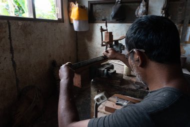 Gianyar,Bali/Endonezya-30 Mayıs 2019: Guwang Village, Gianyar, Bali'de I Wayan Tuges'e ait ahşap gitar atölyesinde bir gitar ustası ölçüyor ve hassas bir gitar parçası olduğundan emin oluyor.