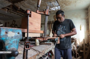 Gianyar,Bali/Endonezya-30 Mayıs 2019: Guwang Village, Gianyar, Bali'de I Wayan Tuges'e ait ahşap gitar atölyesinde bir gitar ustası ölçüyor ve hassas bir gitar parçası olduğundan emin oluyor.