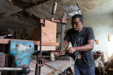 Gianyar,Bali/Endonezya-30 Mayıs 2019: Bir gitar ustası Guwang Village, Gianyar, Bali'de I Wayan Tuges'e ait ahşap gitar atölyesinde ahşaptan klasik gitarlar yapıyor.