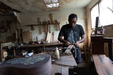 Gianyar,Bali/Endonezya-30 Mayıs 2019: Guwang Village, Gianyar, Bali'de I Wayan Tuges'e ait ahşap gitar atölyesinde bir gitar ustası ölçüyor ve hassas bir gitar parçası olduğundan emin oluyor.
