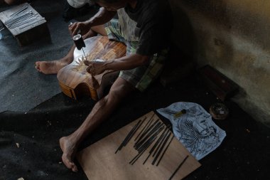 Gianyar,Bali/Endonezya-30 Mayıs 2019: Bir gitar ustası Guwang Village, Gianyar, Bali'de I Wayan Tuges'e ait ahşap gitar atölyesinde ahşaptan yapılmış klasik gitarları oyuyor.