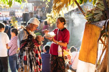 Denpasar,Bali/Endonezya-Haziran 23 2019: Bir Rangda dansçısı, 2019 Bali Sanat Festivali'nde gösteriye başlamadan önce dua ediyor. Dua ettikten sonra kutsal su verilmesini beklerken aşağı bakıyor.
