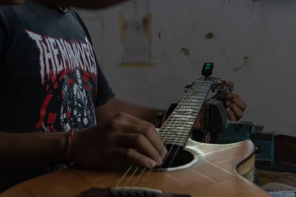 GIANYAR, BALI / INDONÉSIA-MAIO 30 2019: Um artesão de guitarra clássica está emparelhando cordas de guitarra com sua guitarra. Ele também ajustou o tom de guitarra na oficina de guitarra de propriedade de I Wayan Tuges — Fotografia de Stock