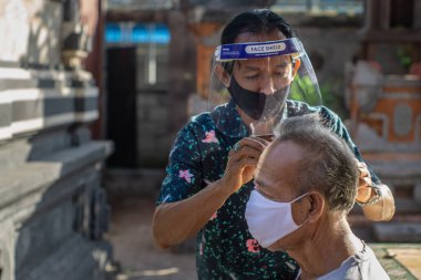 Bir berber ev işi yapıyor. COVID-19 salgını birçok işletmenin kapanmasına neden oldu. Ayakta kalmak için, girişimciler müşterilere gitmeyi tercih ederler. Yeni normal yaşam için sağlık protokollerine bağlı kal.