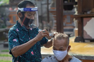 Bir berber ev işi yapıyor. COVID-19 salgını birçok işletmenin kapanmasına neden oldu. Ayakta kalmak için, girişimciler müşterilere gitmeyi tercih ederler. Yeni normal yaşam için sağlık protokollerine bağlı kal.