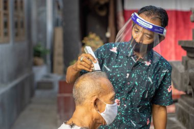 Bir berber ev işi yapıyor. COVID-19 salgını birçok işletmenin kapanmasına neden oldu. Ayakta kalmak için, girişimciler müşterilere gitmeyi tercih ederler. Yeni normal yaşam için sağlık protokollerine bağlı kal.