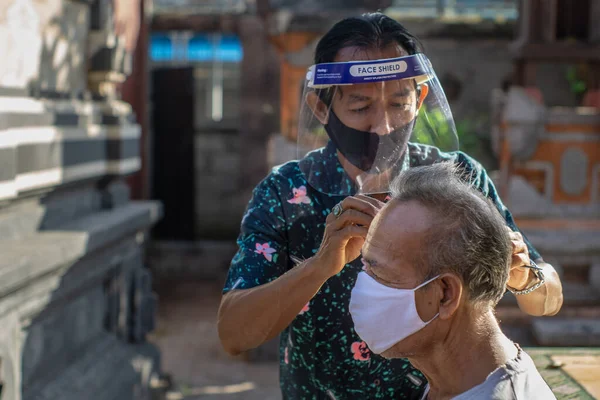 Bir berber ev işi yapıyor. COVID-19 salgını birçok işletmenin kapanmasına neden oldu. Ayakta kalmak için, girişimciler müşterilere gitmeyi tercih ederler. Yeni normal yaşam için sağlık protokollerine bağlı kal.