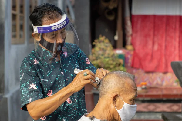 a barber is doing home service. The COVID-19 pandemic has caused many businesses to close. To stay afloat, entrepreneurs prefer to go to customers. Stick to health protocols for new normal life