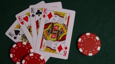 Yeşil keçe yüzeyinde poker kartları ve poker yongaları dönen çekim