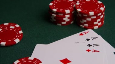 Yeşil keçe yüzeyinde poker kartları ve poker yongaları dönen çekim