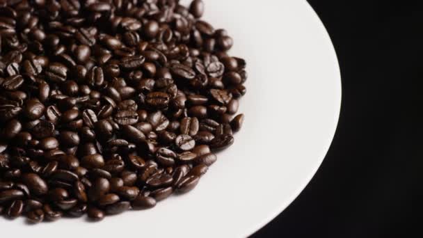 Beyaz bir yüzeyde lezzetli, kavrulmuş kahve çekirdeklerinin dönen çekimi — Stok video