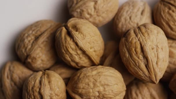 Rotating shot of walnuts in their shells on a white surface — Stock Video