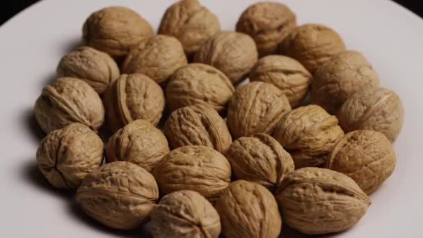 Tiro giratorio de nueces en sus conchas sobre una superficie blanca — Vídeos de Stock