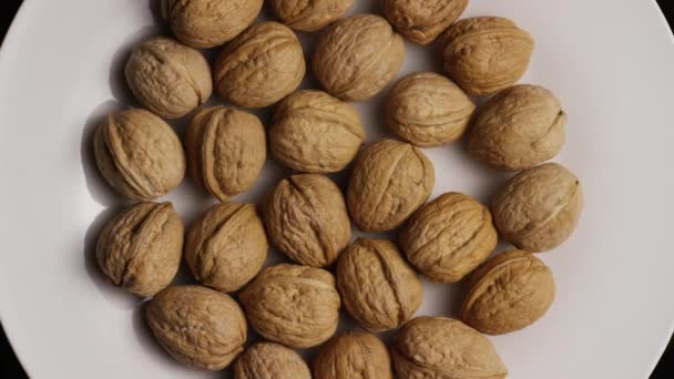 Tiro giratorio de nueces en sus conchas sobre una superficie blanca — Vídeos de Stock