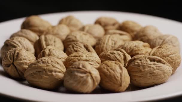 Rotating shot of walnuts in their shells on a white surface — Stock Video