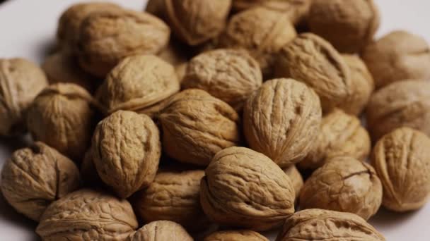 Tiro giratorio de nueces en sus conchas sobre una superficie blanca — Vídeos de Stock