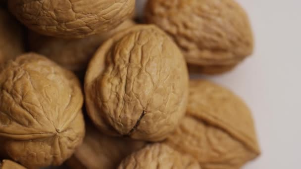 Rotating shot of walnuts in their shells on a white surface — Stock Video