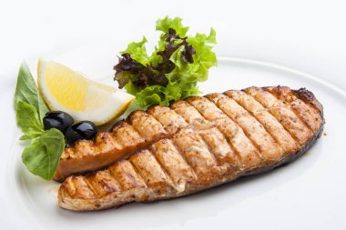 Beyaz plaka üzerinde limon ile somon biftek.