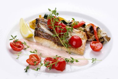 Beyaz bir çanak üzerinde sebze ile Sudak.