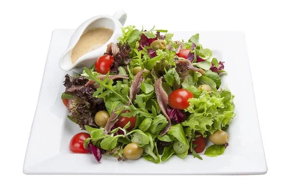 Салат з анчоусами та овочами на білій тарілці — стокове фото