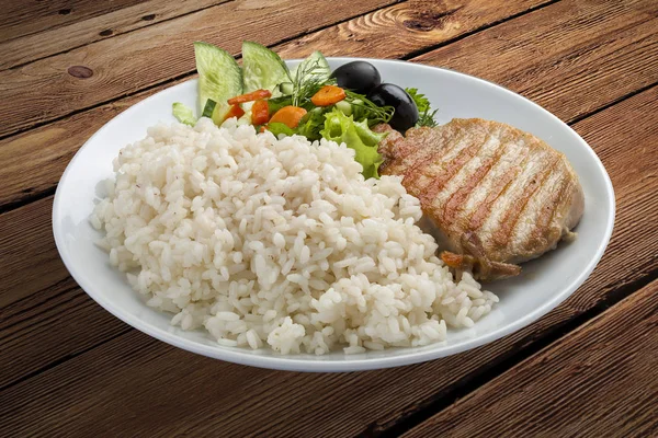 Rice porridge with chicken and vegetables on a wooden background